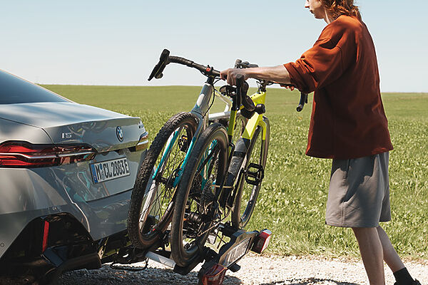 BMW Fahrradheckträger Person befestigt zwei Fahrräder auf einem Heckträger an einer BMW Limousine.
