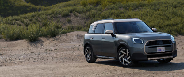 MINI Countryman – Exterieur Grauer MINI Countryman in vorderer Dreiviertelansicht vor einer natürlichen Landschaft.