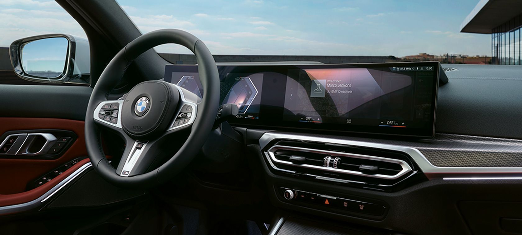 Cockpit der BMW 3er Limousine mit breitem Display Cockpit der BMW 3er Limousine mit breitem Display, Lenkrad und roten Türpolstern.