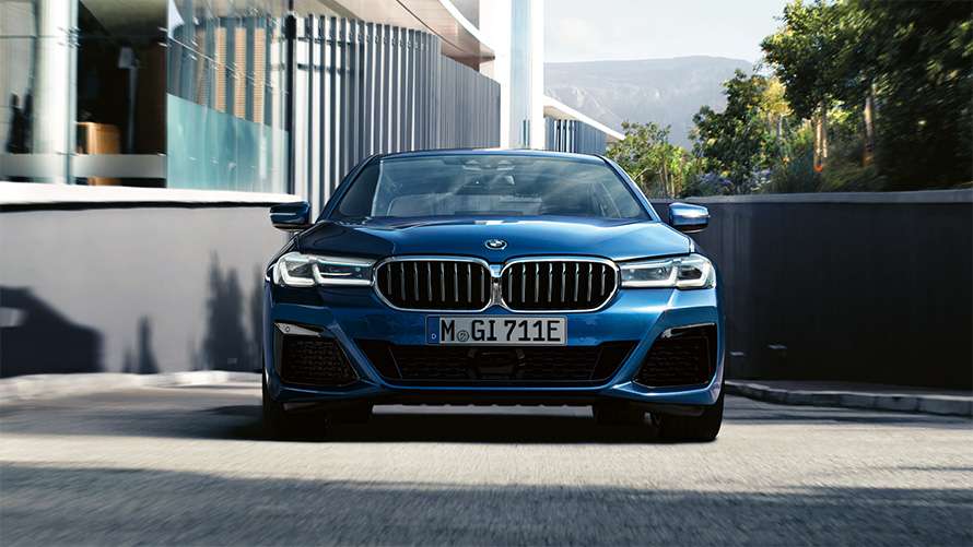 Blaue BMW 5er Limousine in Frontansicht vor einem Haus Blaue BMW 5er Limousine in Frontansicht vor einem Haus.