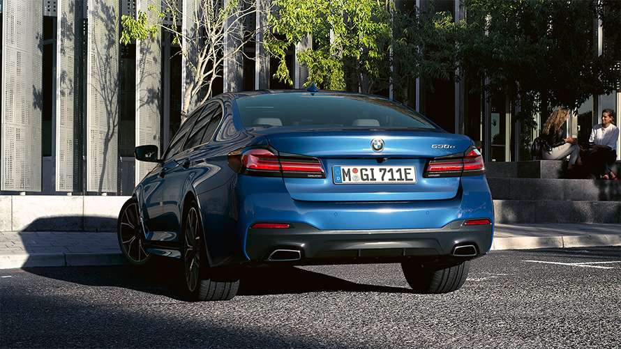 Blaue BMW 5er Limousine Blaue BMW 5er Limousine, schräg von hinten vor einem modernen Gebäude.