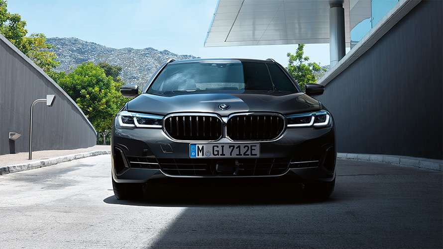 Dunkler BMW 5er Touring in Frontansicht vor einem modernen Gebäude Dunkler BMW 5er Touring in Frontansicht vor einem modernen Gebäude.