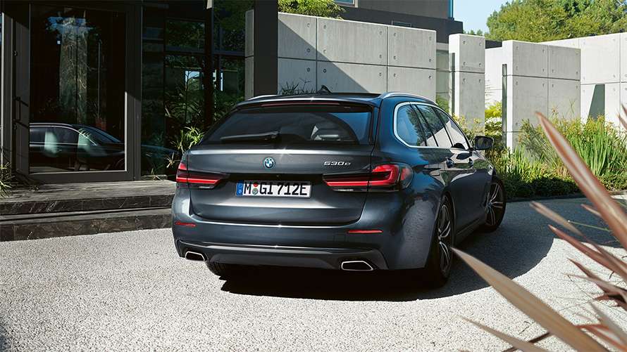 Dunkler BMW 5er Touring steht vor einem Haus Dunkler BMW 5er Touring steht vor einem Haus, schräg von hinten.