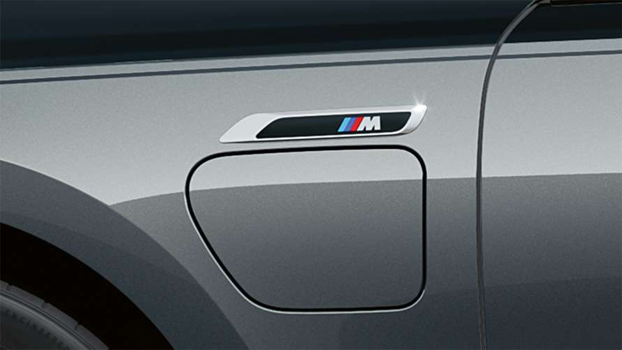 Detail des seitlichen Ladeanschlusses mit M-Emblem an einer grauen Detail des seitlichen Ladeanschlusses mit M-Emblem an einer grauen BMW 7er Limousine.