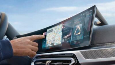 Hand bedient das breite Navigationsdisplay im Armaturenbrett einer BMW Eine Hand bedient das breite Navigationsdisplay im Armaturenbrett einer BMW 3er Limousine.