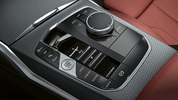 iDrive-Controller und Gangwahlschalter in der Mittelkonsole der BMW 3er iDrive-Controller und Gangwahlschalter in der Mittelkonsole der BMW 3er Limousine neben roter Polsterung.