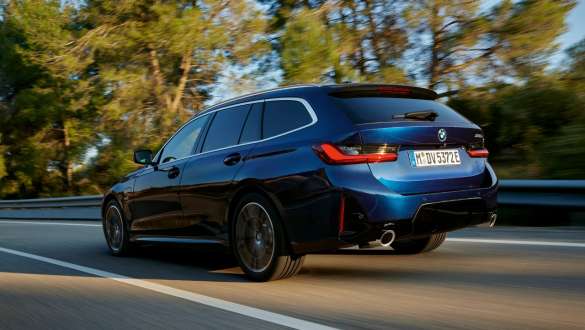 Blauer BMW 3er Touring fährt auf einer von Bäumen gesäumten Straße Blauer BMW 3er Touring fährt auf einer von Bäumen gesäumten Straße, schräg von hinten.