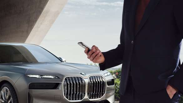 Person hält einen Schlüssel neben der Front einer silbernen BMW 7er Limousine Eine Person hält einen Schlüssel neben der Front einer silbernen BMW 7er Limousine.