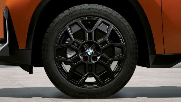 Nahaufnahme eines schwarzen Leichtmetallrades an einem orangefarbenen BMW X1 Nahaufnahme eines schwarzen Leichtmetallrades an einem orangefarbenen BMW X1.