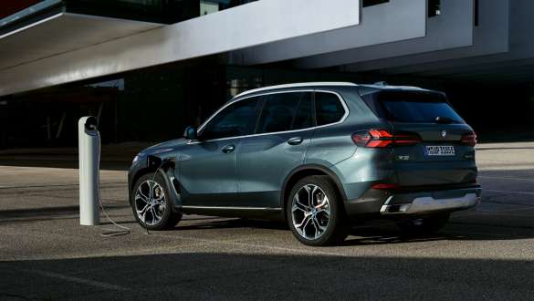 Graugrüner BMW X5 steht neben einer Ladesäule Graugrüner BMW X5 steht neben einer Ladesäule, schräg von hinten.